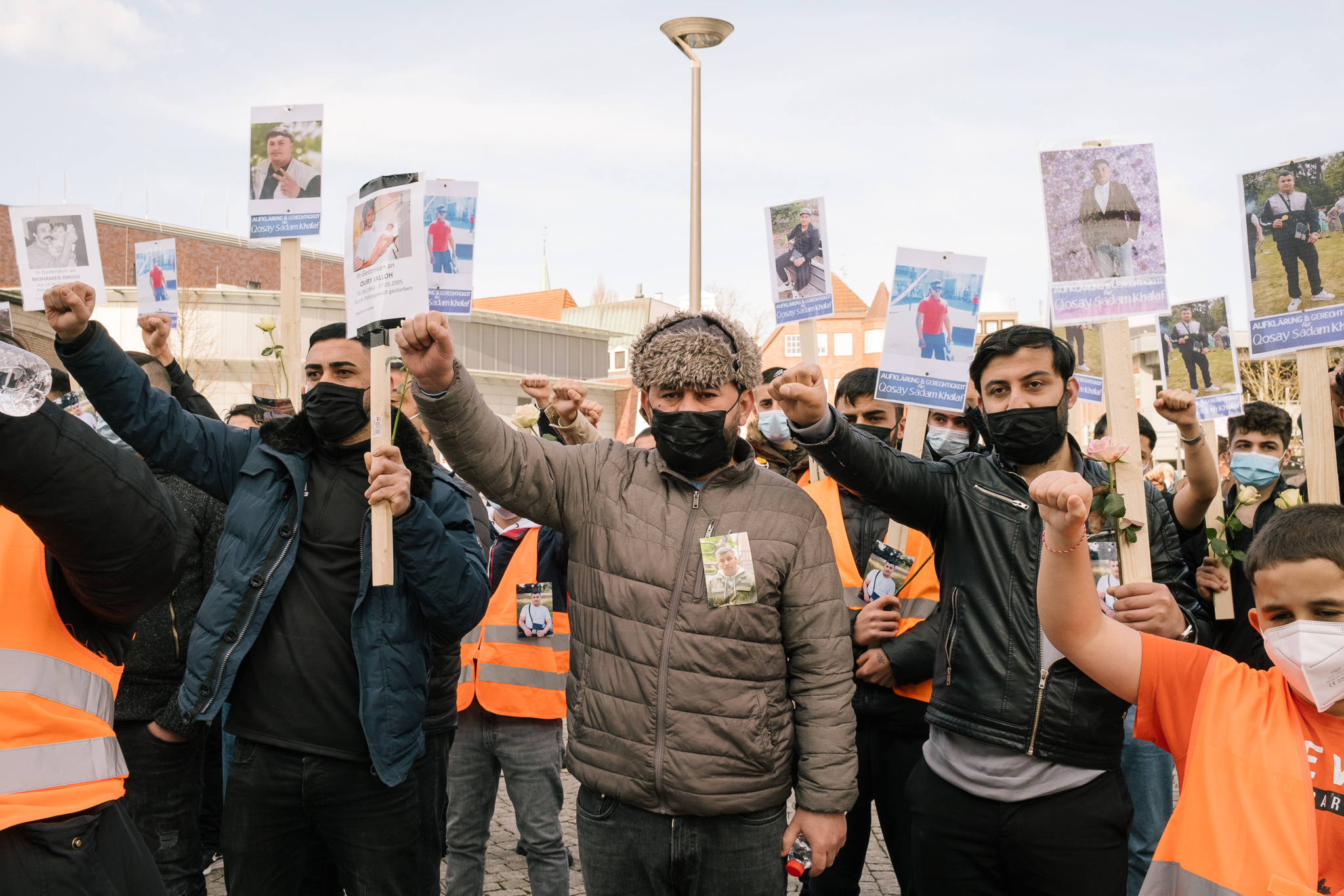Participants of a rally in Delmenhorst hold a minute of silence raising their fists in memory of Qosay Khalaf. April 3rd, 2021, Delmenhorst 